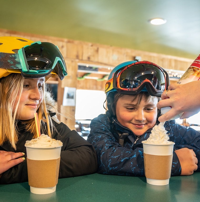 young skier getting whipped cream on hot cocoa